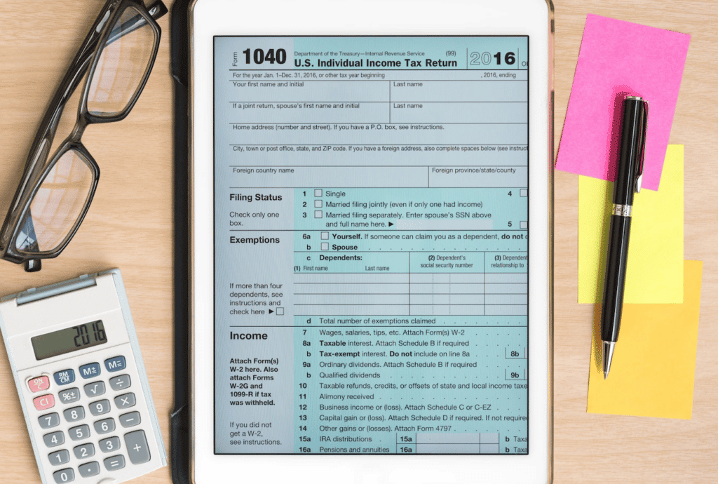 Tablet com formulário de declaração de impostos de renda ao lado de calculadora e materias 