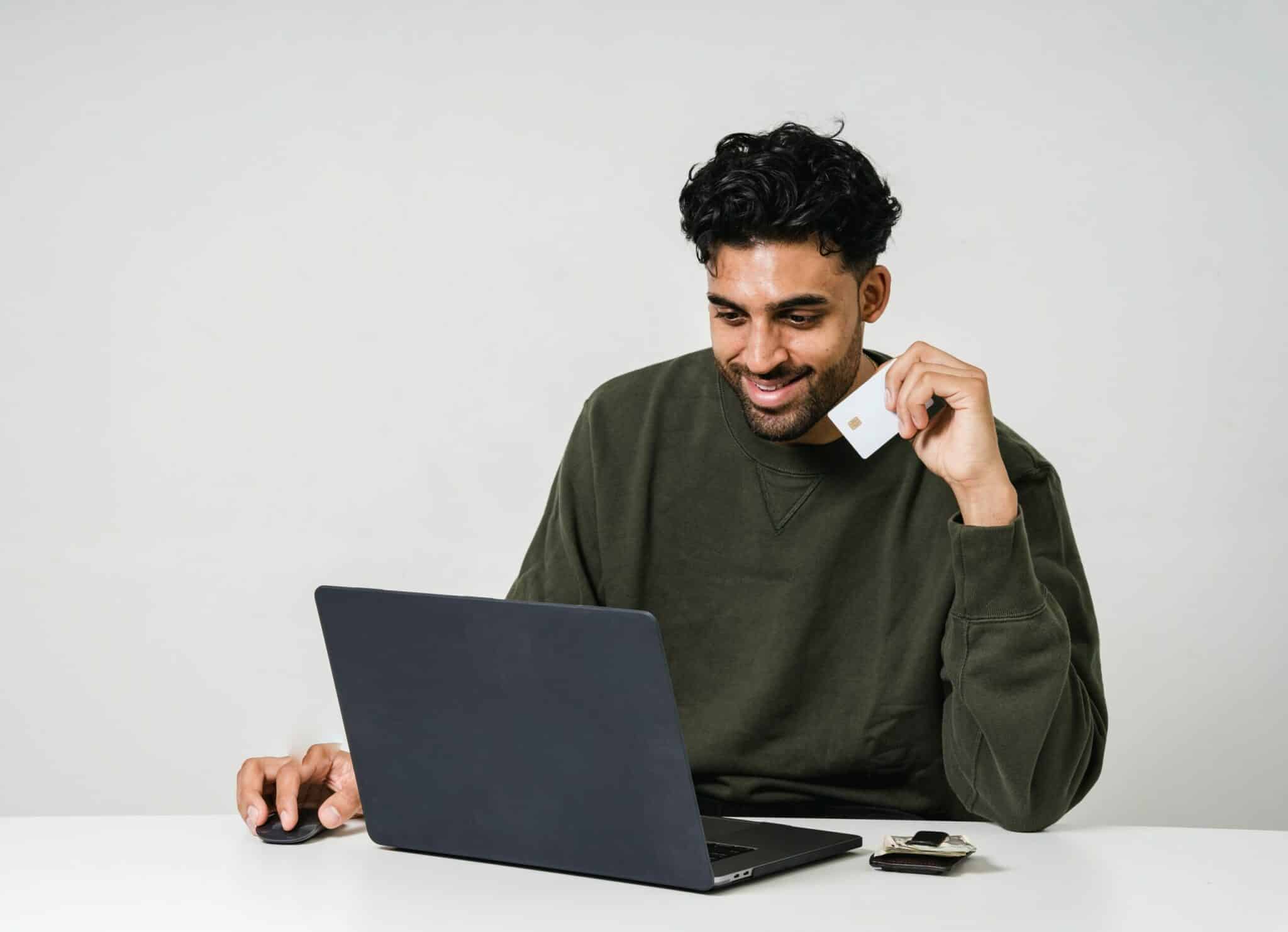 man using laptop and holding debit card