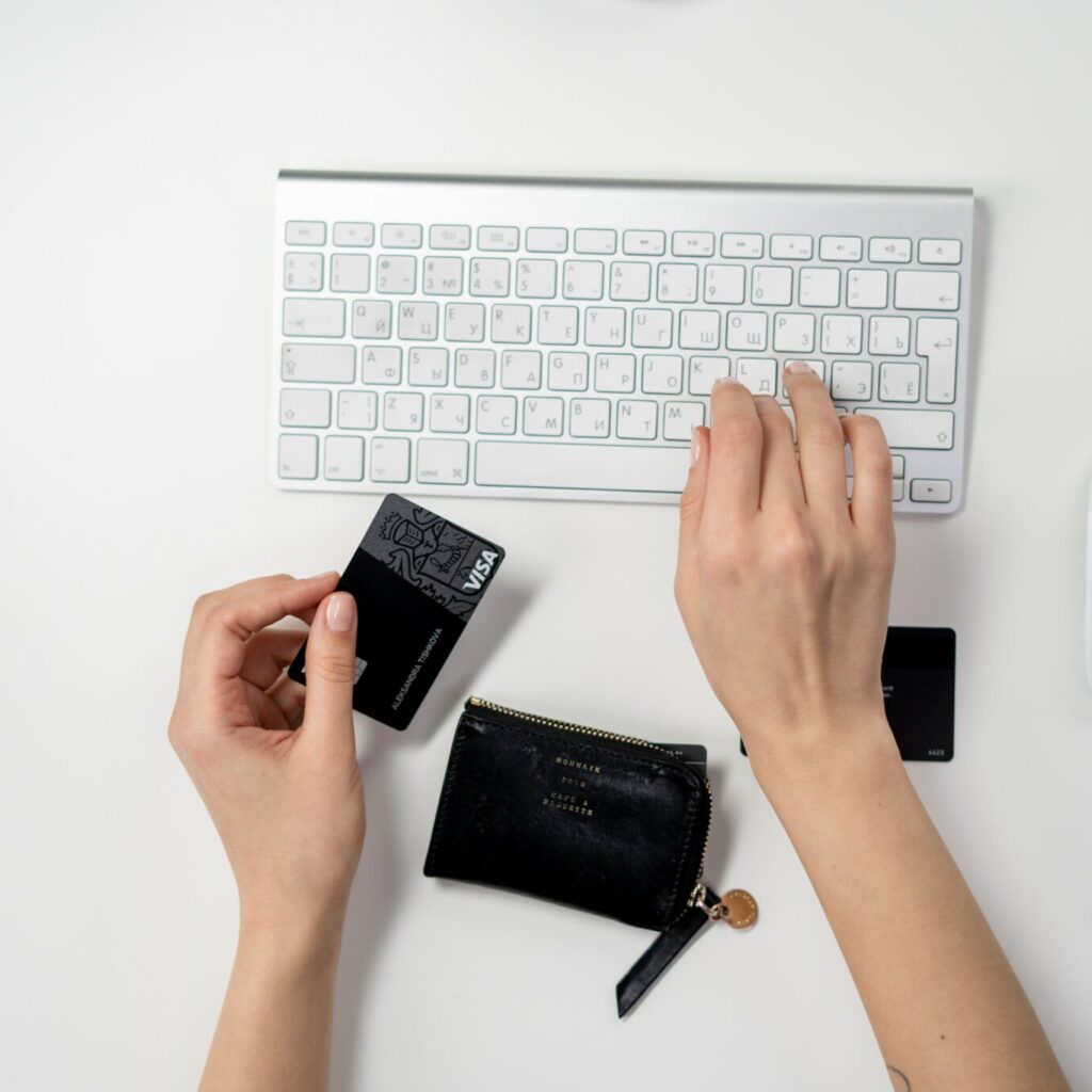 Person typing on keyboard and holding card