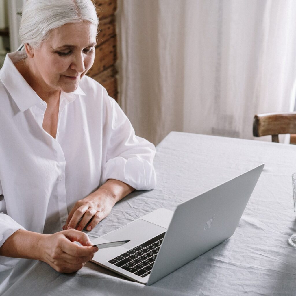 Older woman sitting ata table in front of a laptop shopping online