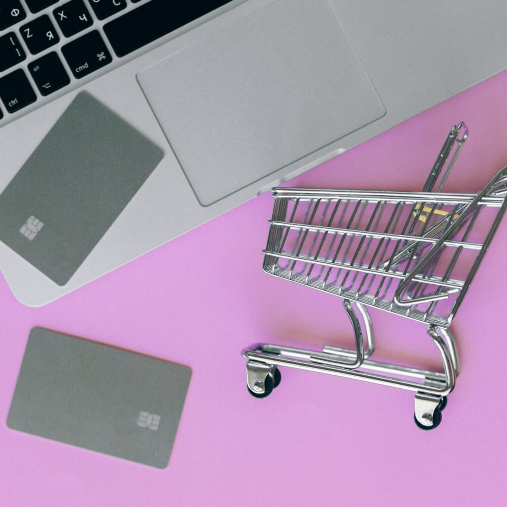 Laptop with credit cards on top and miniature shopping card representing Black Friday Predictions