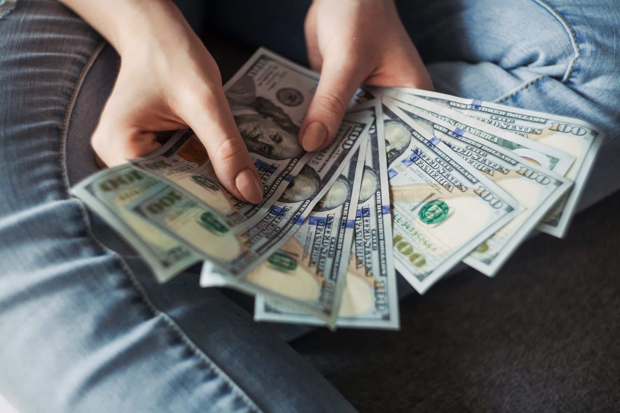 Mãos femininas segurando notas de dólar