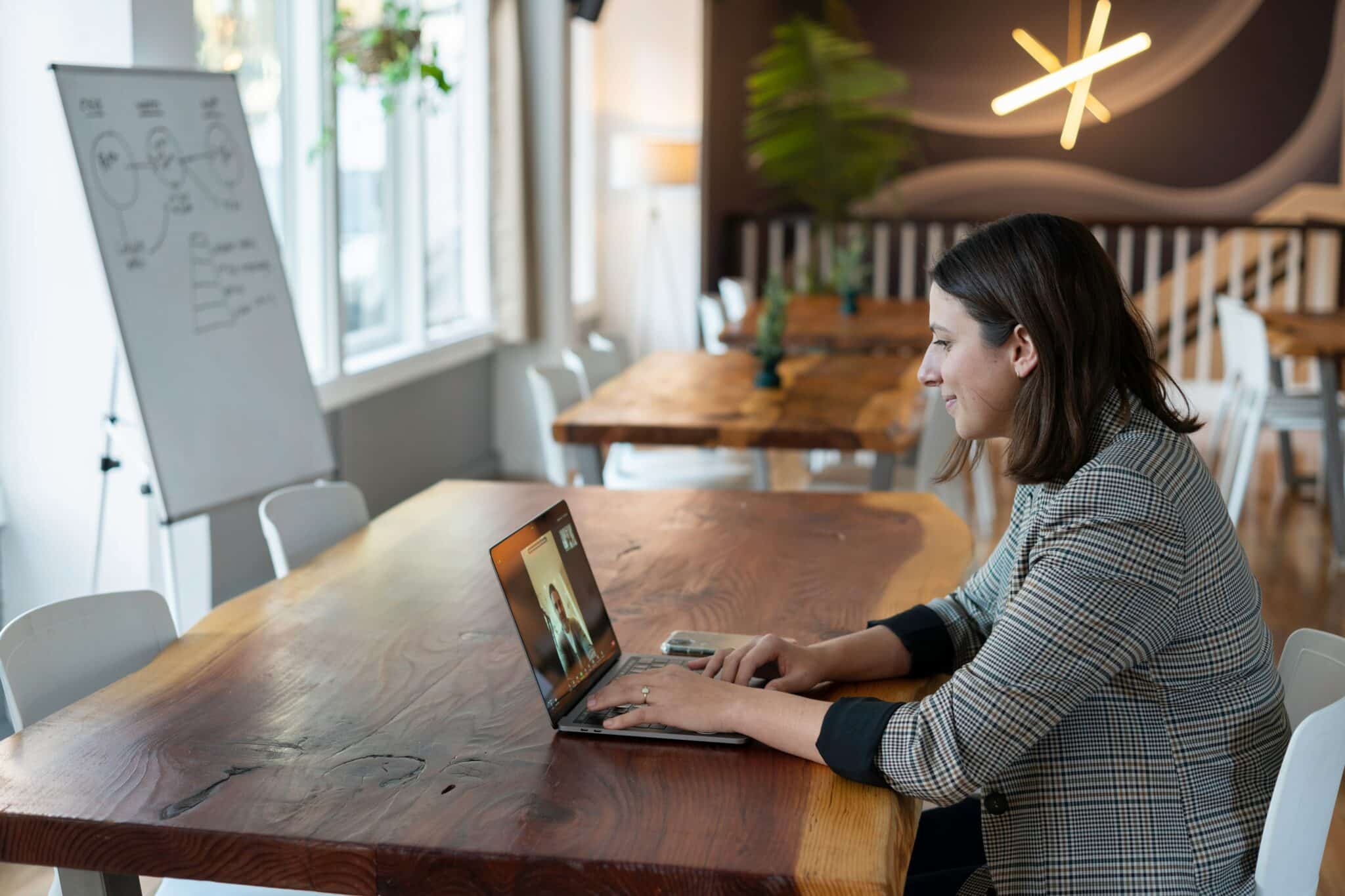 Empreendedora em coworking gerenciando sua empresa em laptop