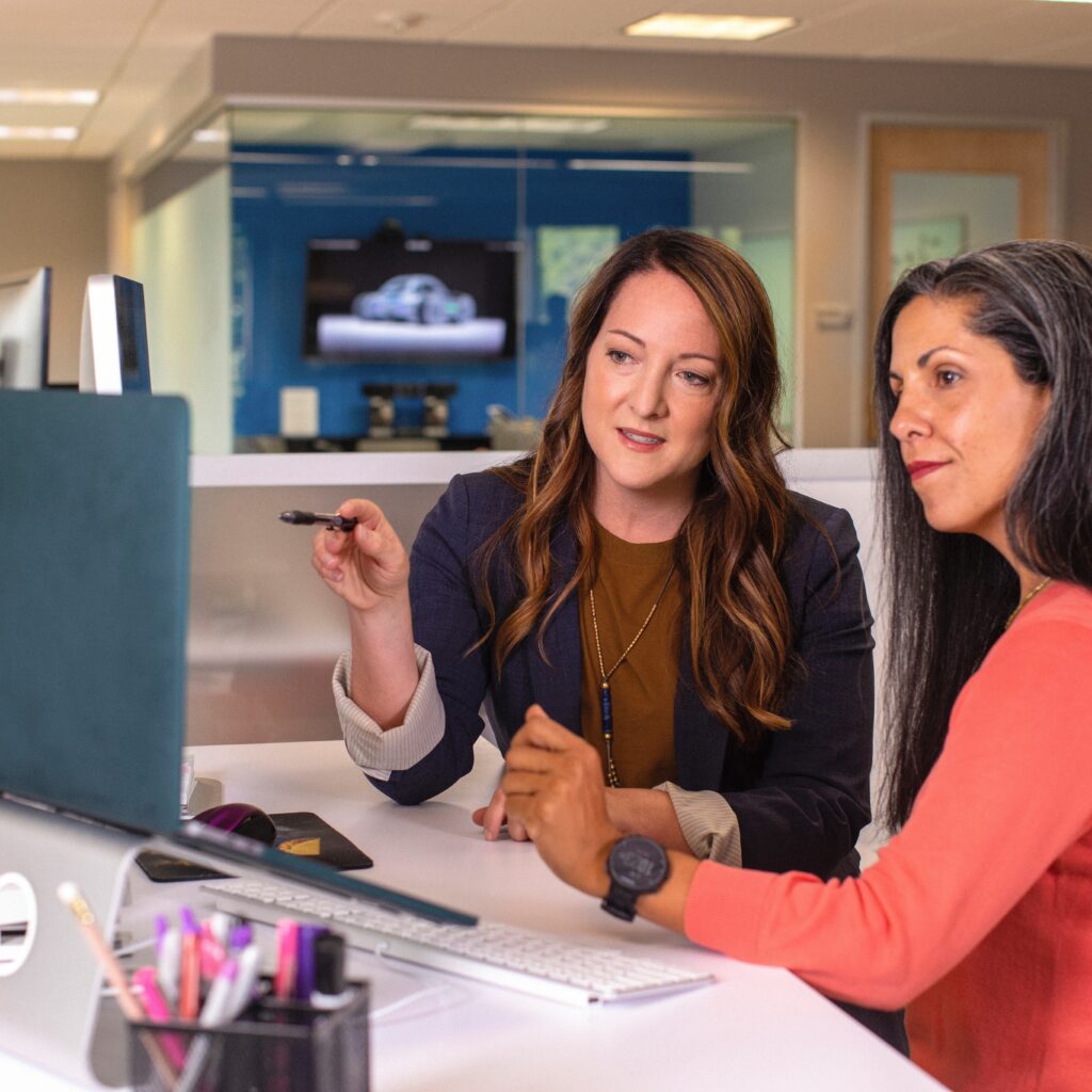 Two women talking and looking at a computer screen 