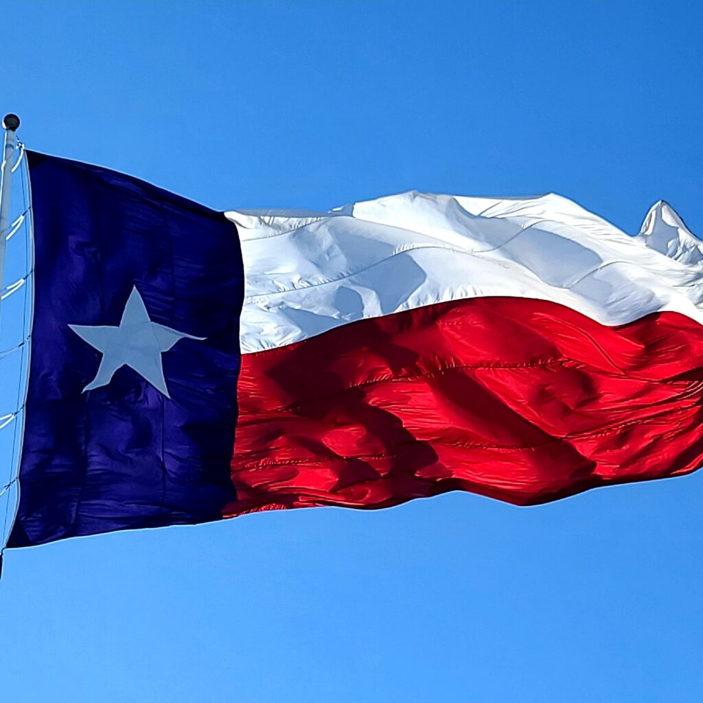 Texas flag under a bright blue sky.