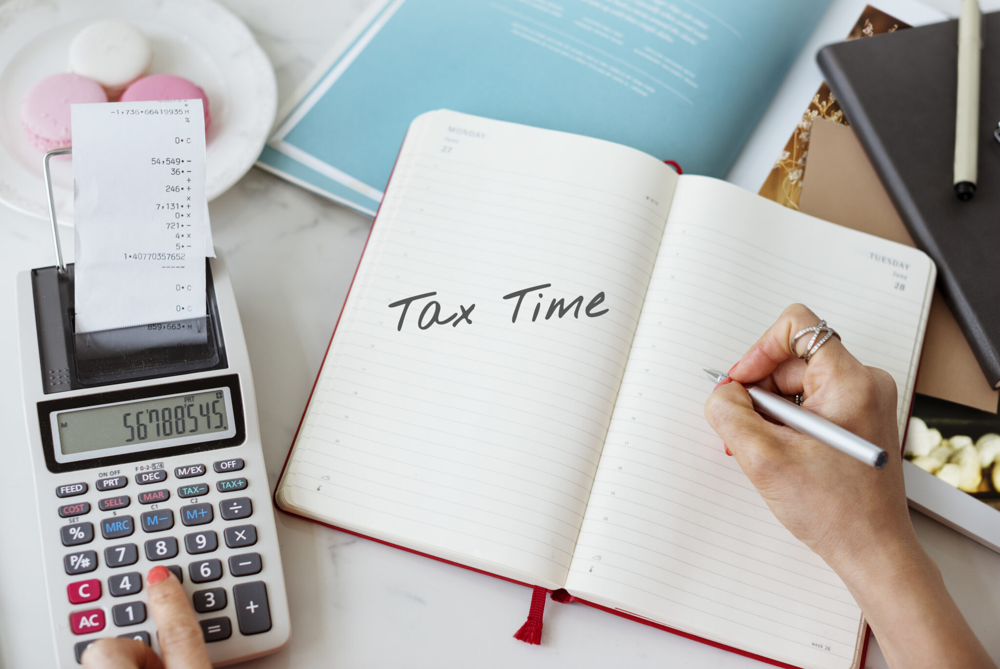 Pessoa trabalhando nos seus impostos para Tax Season com caderno e calculadora