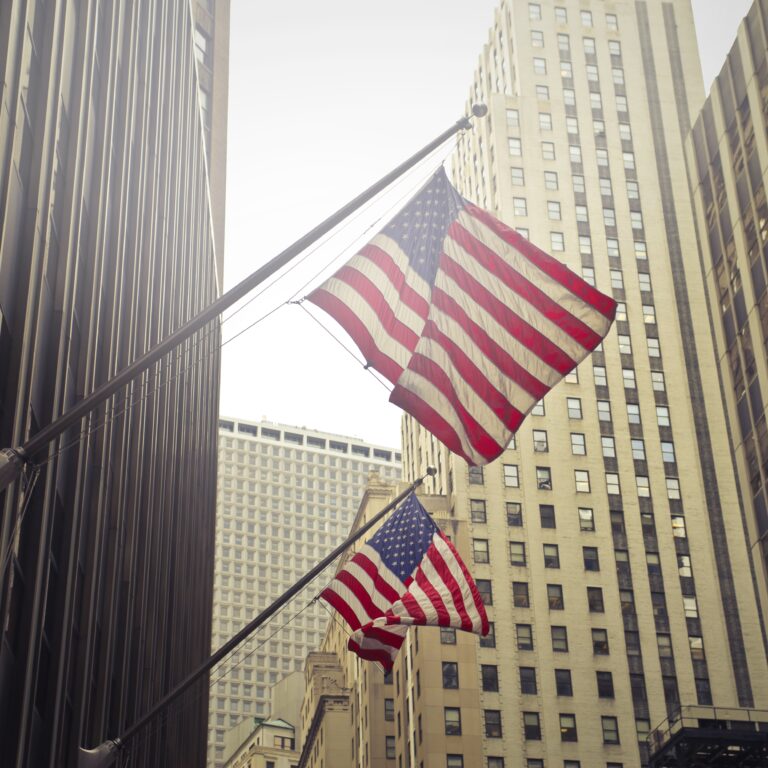 two american usa flags high rise in a building.