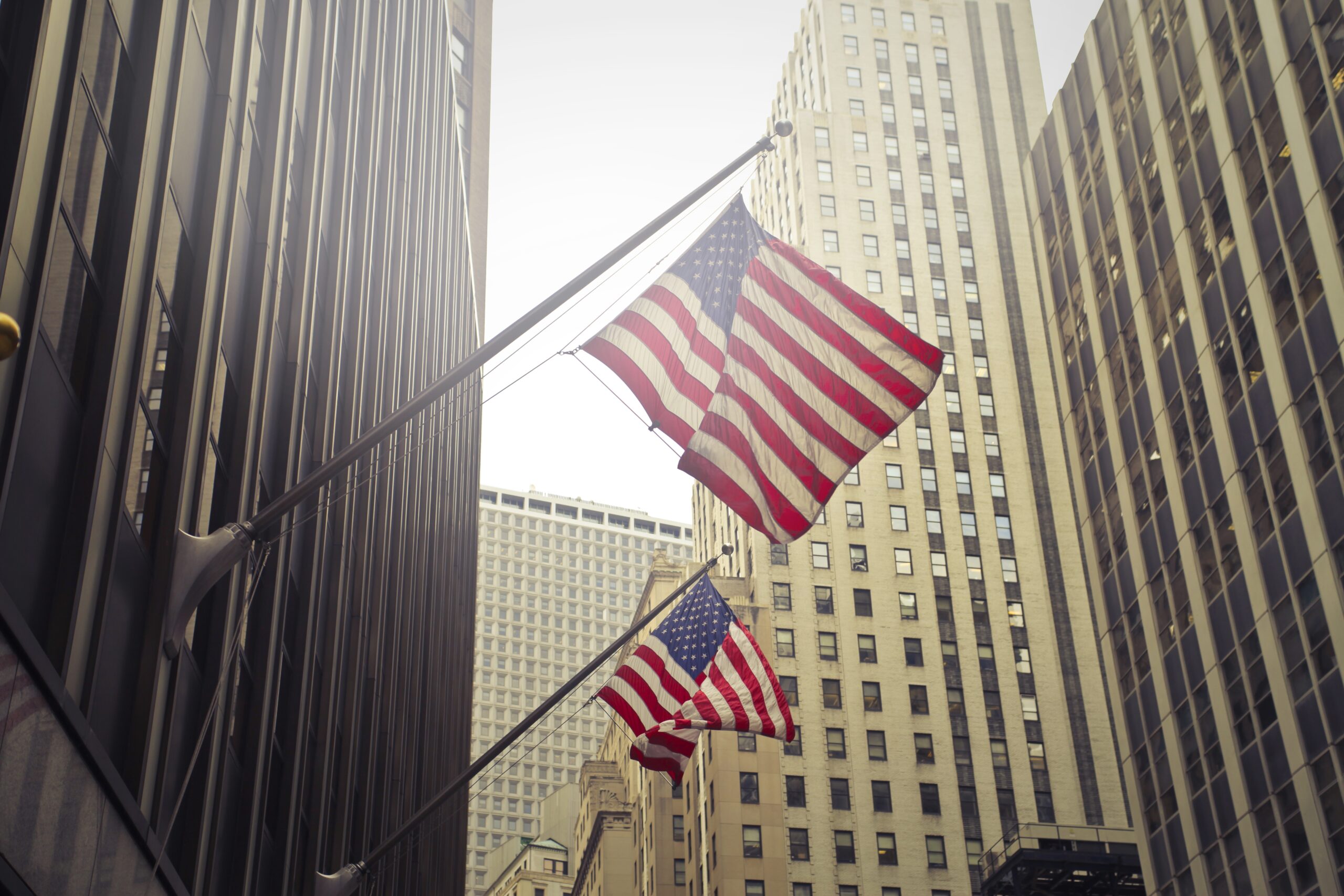 two american usa flags high rise in a building.