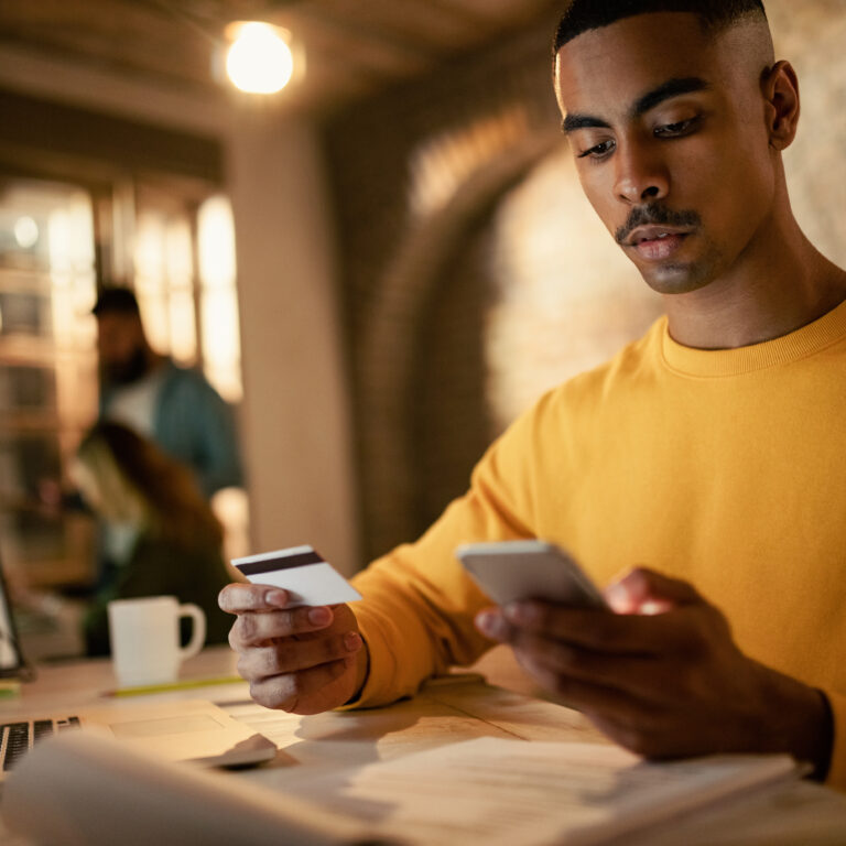 young businessman using credit card on his smartphone while shopping online
