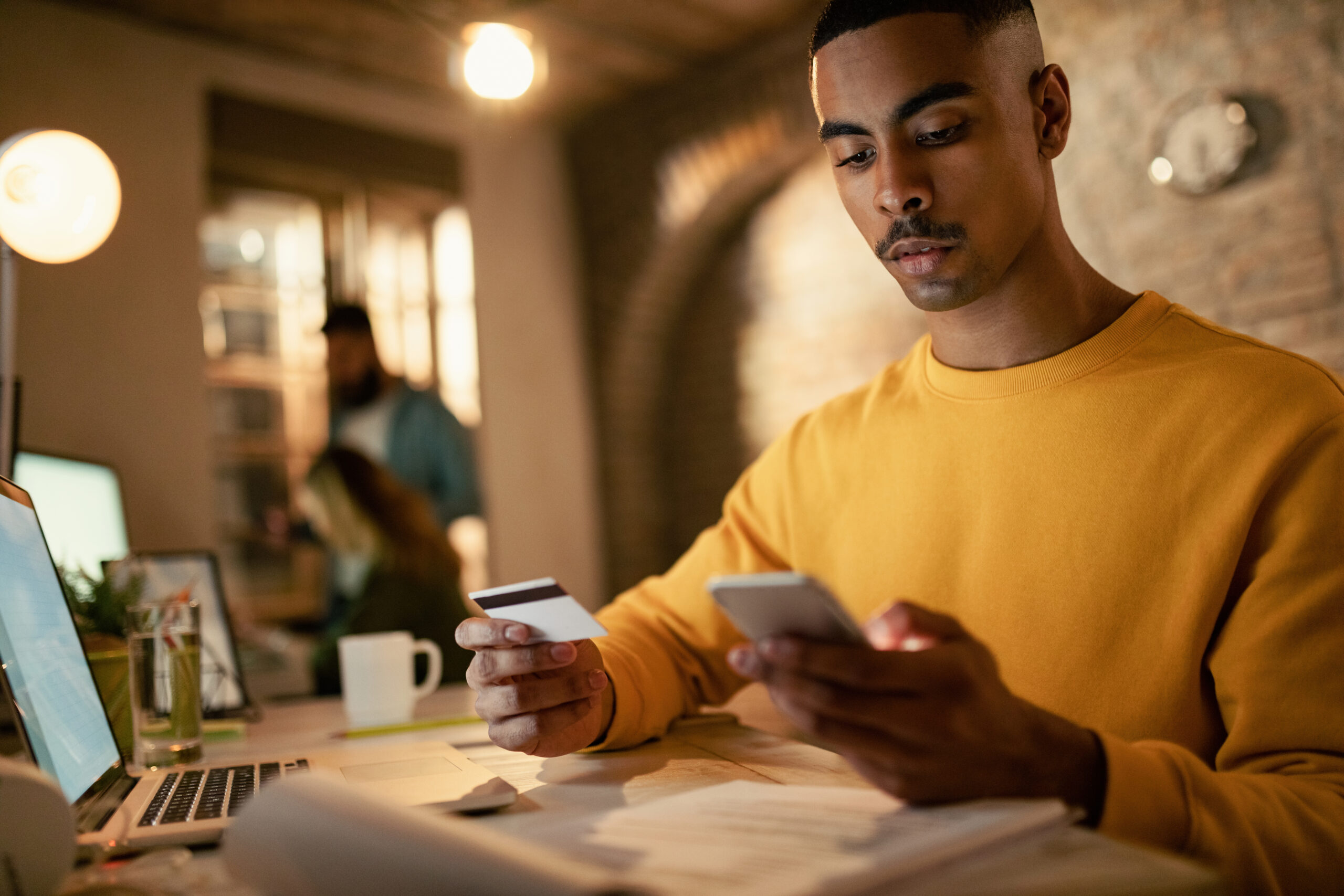 young businessman using credit card on his smartphone while shopping online