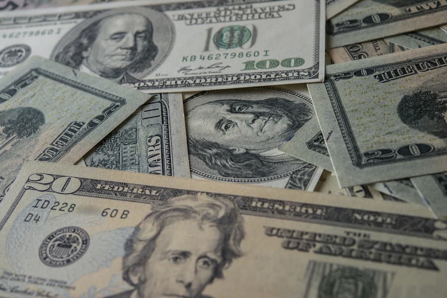 Primer plano de varios billetes de dólares estadounidenses, incluidas las denominaciones de $20, $50 y $100, esparcidos sobre una superficie.